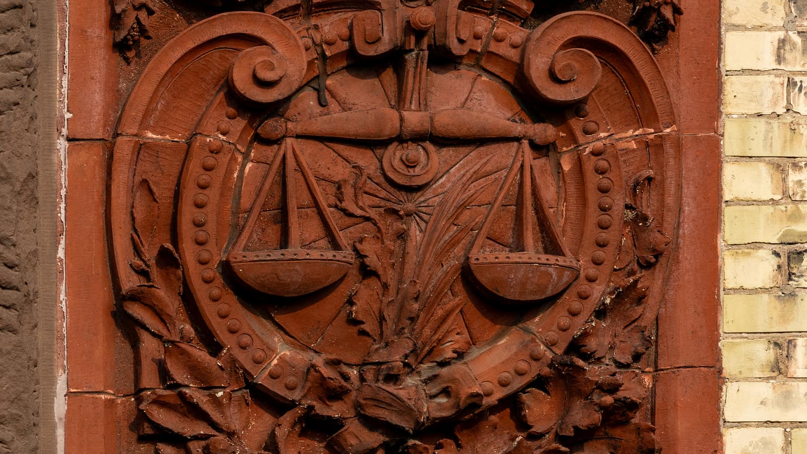 Terracotta relief of the scales of justice on a brick wall
